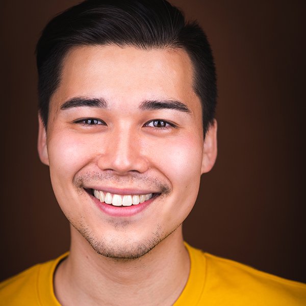 Playwright Sam Hamashima smiling in a yellow tee shirt